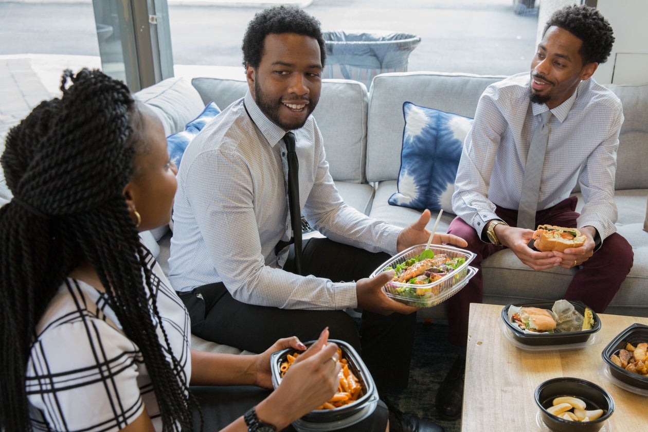 Colleagues sharing meals together in a relaxed office lounge